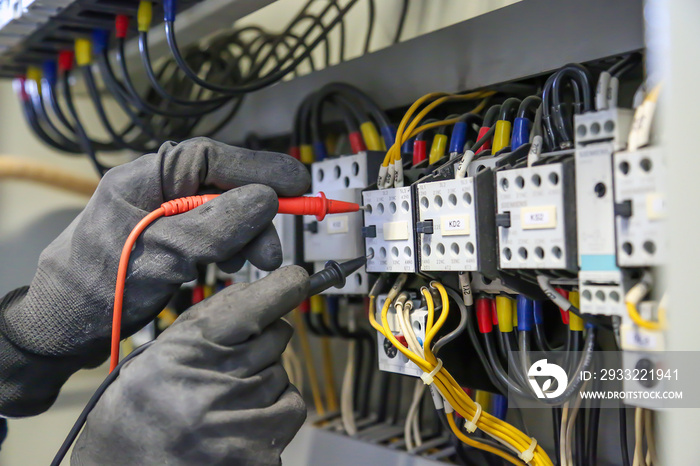 电气工程师使用数字万用表测量设备检查电流电压