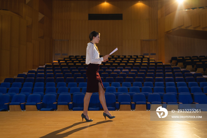 Businesswoman practicing and learning script while walking in the auditorium