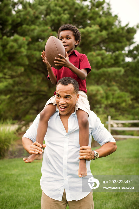 Man carrying his son on shoulder outdoors