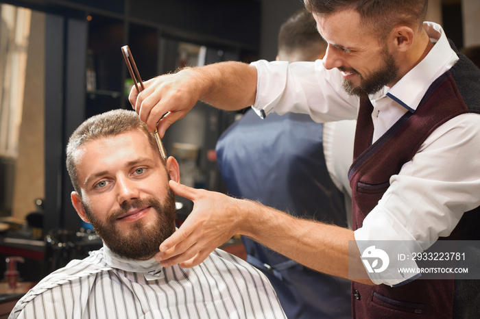 Front view of satisfied male in barber shop getting haircut