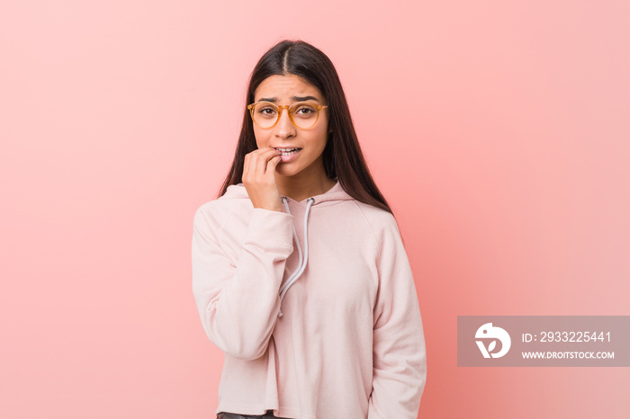 Young pretty arab woman wearing a casual sport look biting fingernails, nervous and very anxious.