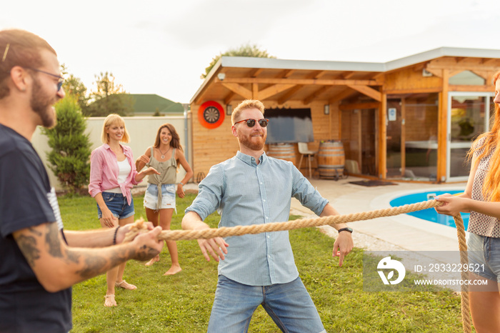 Friends doing limbo dance at summertime poolside party