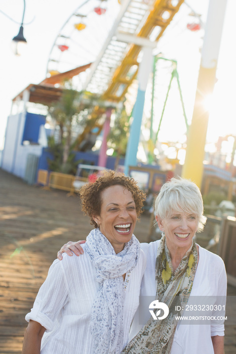 Happy senior women friends at sunny amusement park