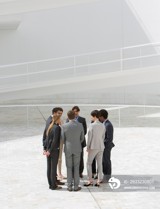 Business people talking in circle on sunny patio