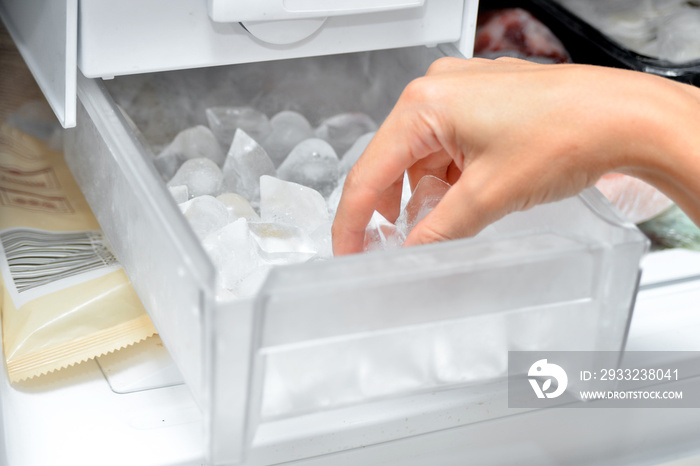 一个女人从制冰机里拿出冰块来冷却饮料。
