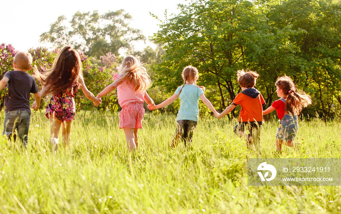 a group of children playing and running in the park on a green gozon.