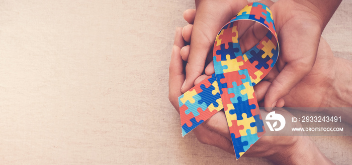 Hands holding puzzle ribbon for autism awareness banner