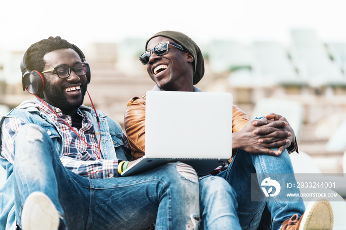 Two black race friends having fun with laptop.