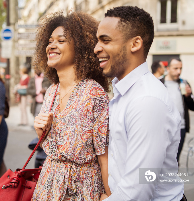 Happy couple talking looking away while standing on city street