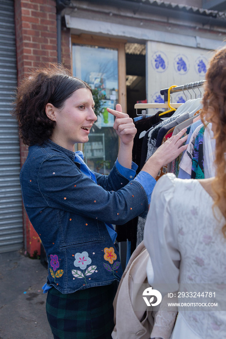 Two trans friends checking out a vintage clothing market