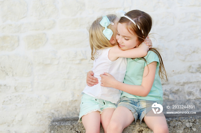 Two adorable little sisters laughing and hugging