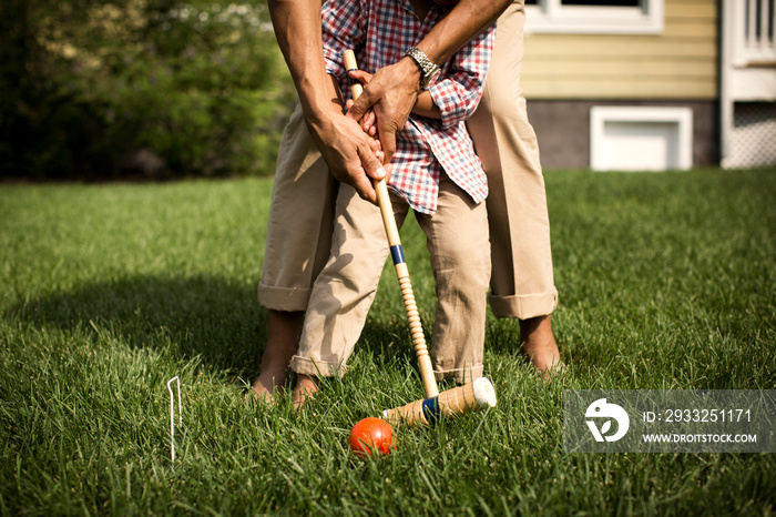 Low-section of father and son (2-3) playing polo