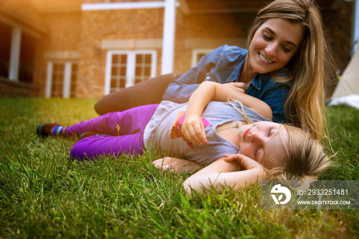 Mother and daughter (6-7) lying on grass in back yard