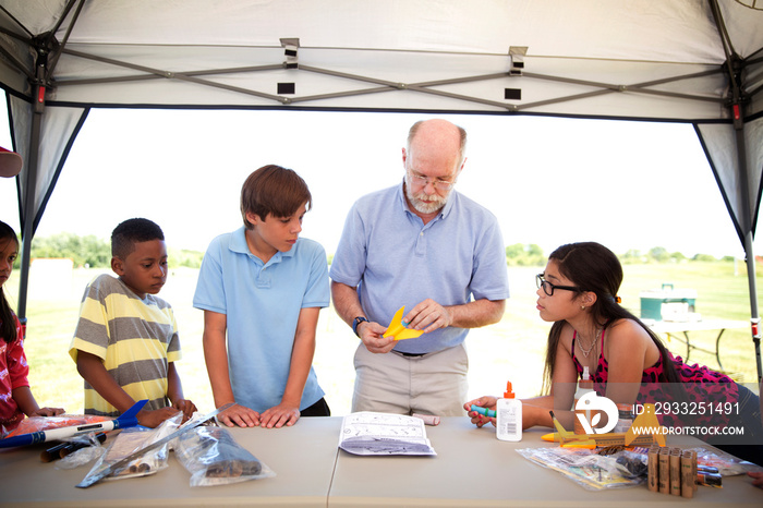 Senior man assembling model kit with group of kids (8-9, 10-11)