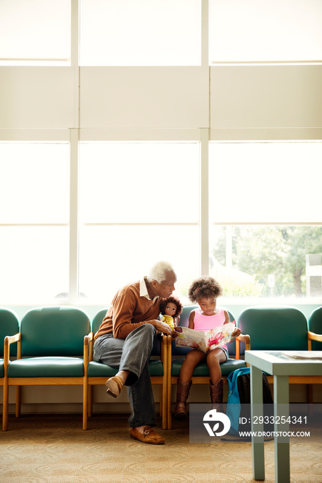 Girl (4-5) sitting with grandfather in waiting room