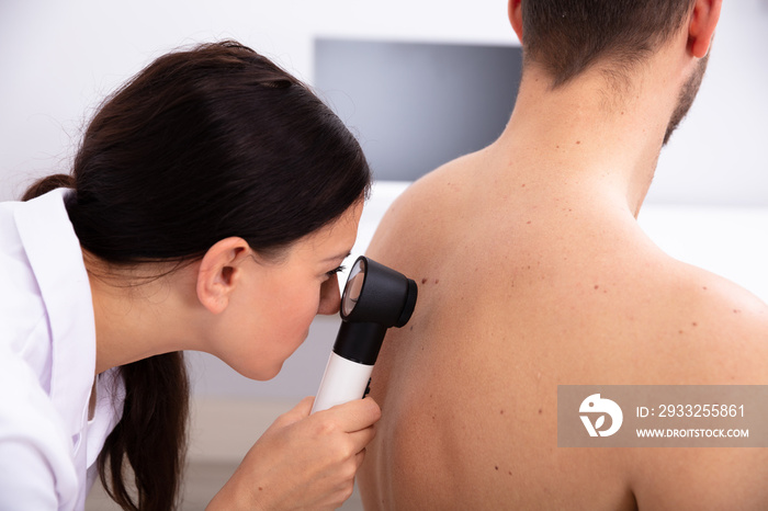 Doctor Examining Pigmented Skin On Mans Back