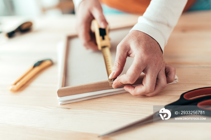 Female carpenter tape measuring picture frame in workshop