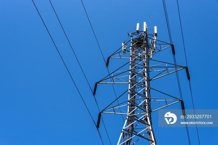 Lattice self-supporting steel utility tower with power lines and panel antennas for a wireless commu