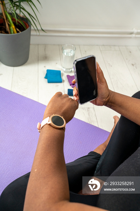 女性在瑜伽运动中使用智能手表和智能手机