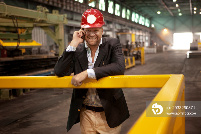 Portrait of man talking on smartphone in factory