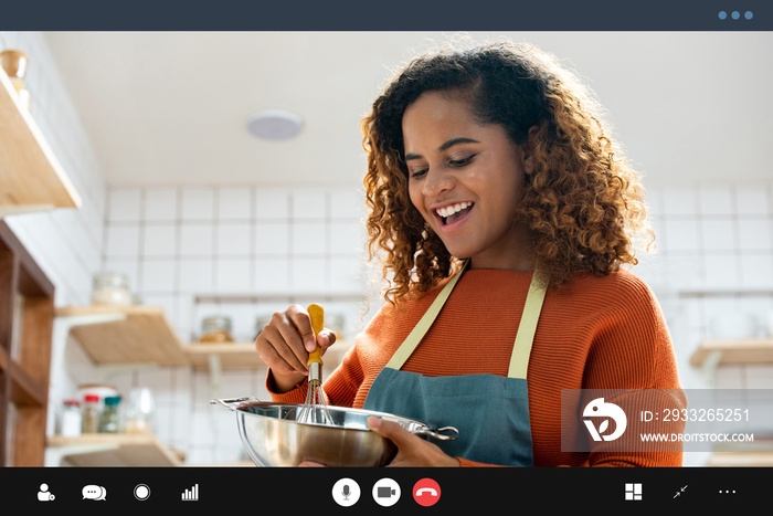 年轻快乐的非裔美国妇女在空闲时间在家厨房做饭时打视频电话