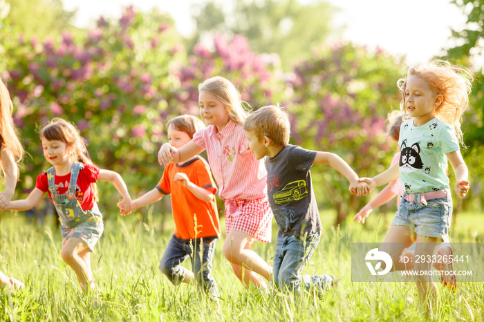 A group of happy children of boys and girls run in the Park on the grass on a Sunny summer day . The