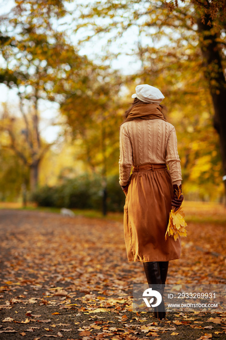 秋天公园里走在外面的黄叶时髦女人