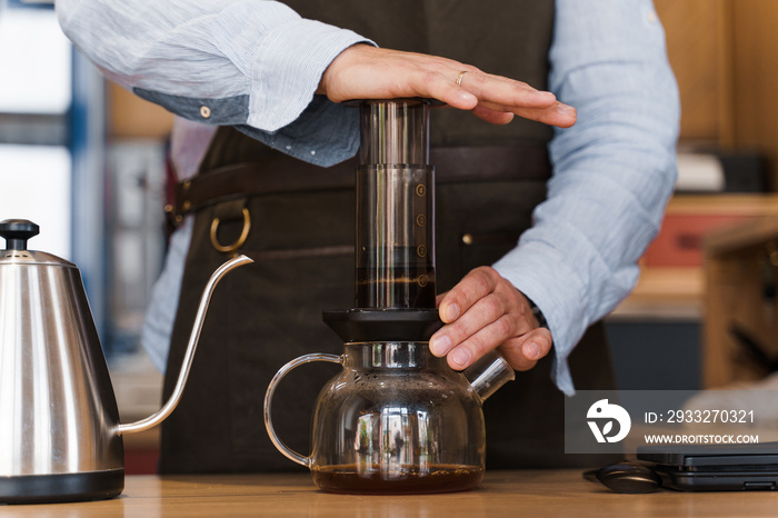 Aeropress咖啡特写：咖啡师按到设备上，咖啡滴从Aeropress倒到壶里。