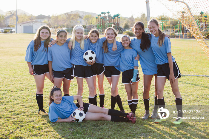 Portrait of smiling soccer players on grassy field against sky