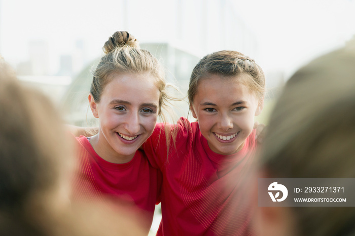 Girl soccer players with their arms around each other.