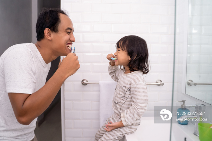 kid learn how to brush teeth with dad