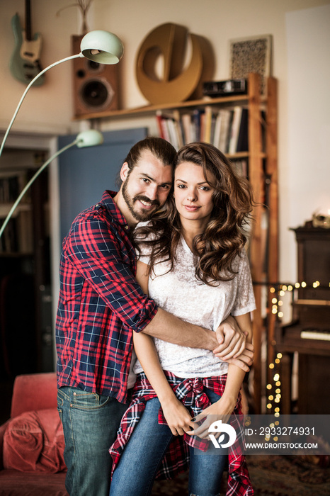 Portrait of young couple embracing in living room