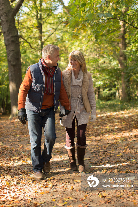 Mature couple holding hands and walking in autumn park