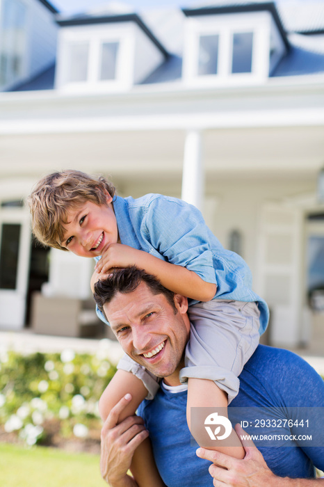 Portrait happy father carrying son on shoulders