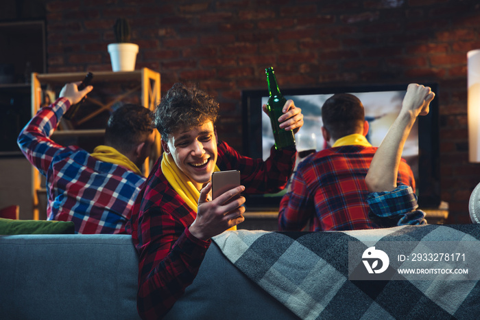 Group of friends watching TV, sport match together. Emotional man cheering for favourite team, celeb