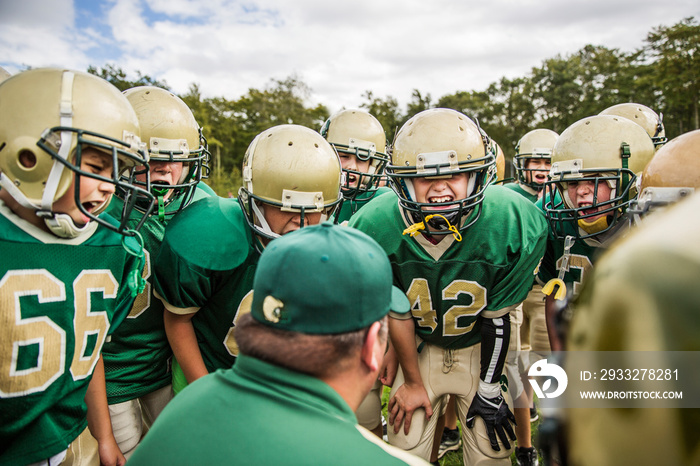 American football team talking with coach in field