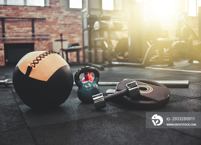 Disassembled barbell, medicine ball, kettlebell, dumbbell lying on floor in gym. Sports equipment fo