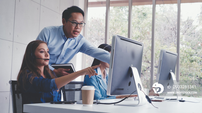 Customer support agent or call center with headset works on desktop computer while supporting the cu