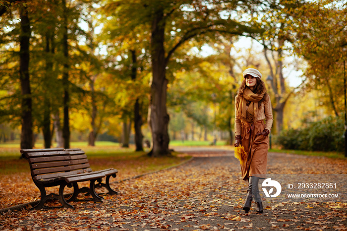 happy woman with yellow leaves walking outdoors in autumn park