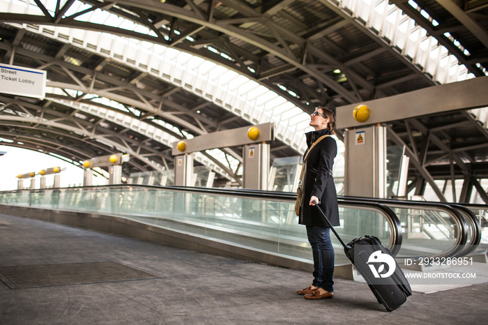 Side view of woman with luggage standing at railway station