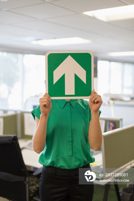 Businesswoman covering face with arrow sign