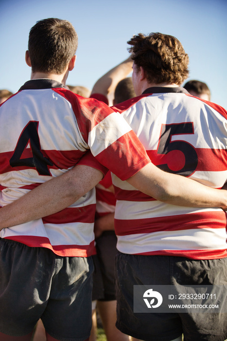 Rear view of rugby players standing in field