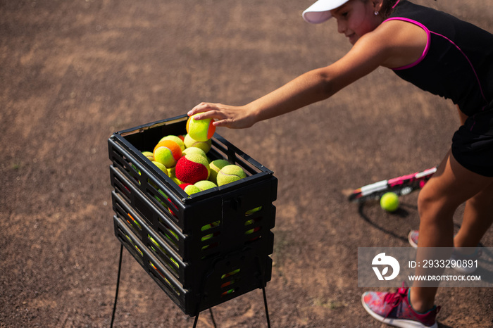职业年轻网球运动员女孩，从特殊的盒子里拿一个新球。