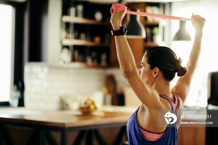 Sportswoman working out with a power band at home.