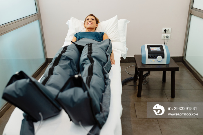 Happy woman during pressotherapy treatment at health spa.