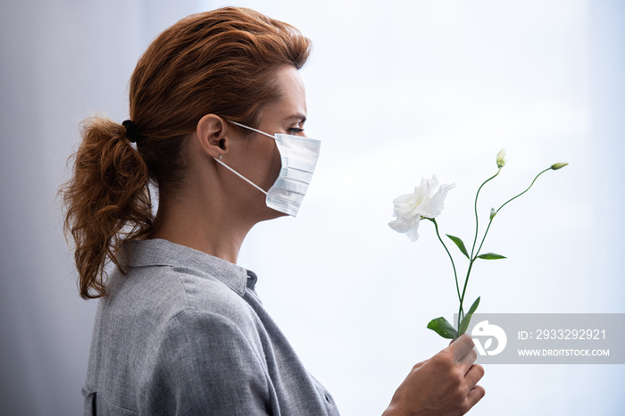 戴医用口罩的妇女看花的侧视图