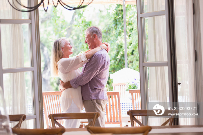 Happy senior couple hugging in patio doorway