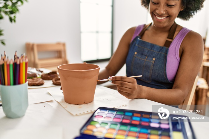 年轻的非裔美国妇女在艺术工作室自信地画粘土壶微笑