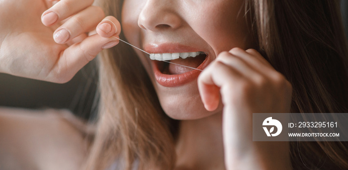 Unrecognizable young girl cleaning teeth with dental floss, close up