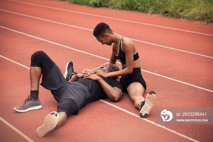 High angle view of tired athlete boyfriend resting on girlfriends leg at sports track